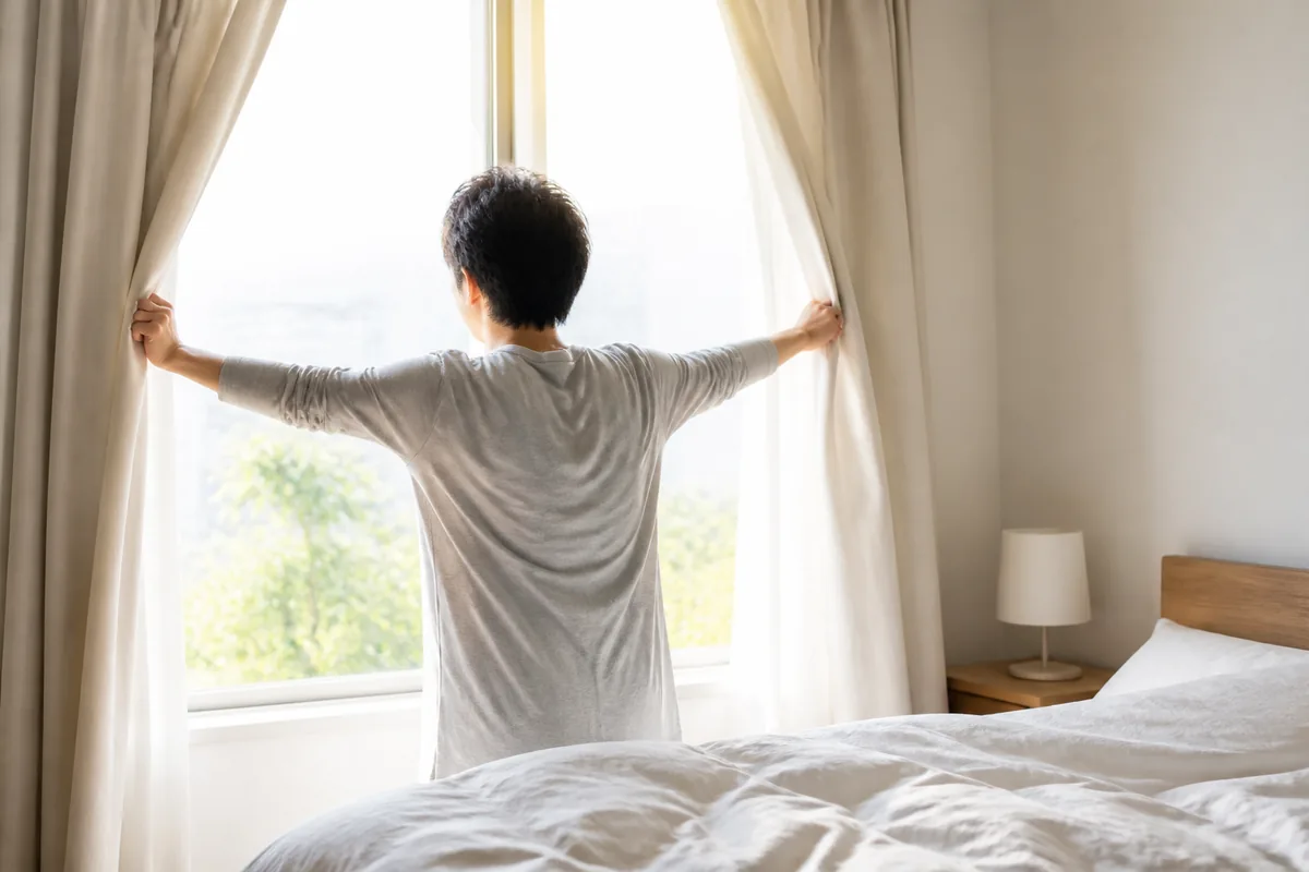 起床後すぐにカーテンを開けて朝日を室内に入れる様子