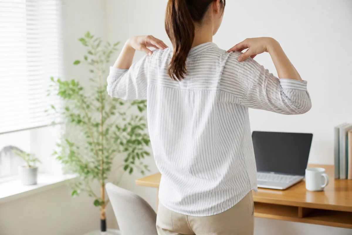 仕事の合間に立ち上がって肩を回す休憩の様子